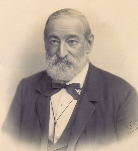 Herr Anton Gerstner bereits als älterer Herr mit Bart und Fliege blickt ernst in die Kamera, gekleidet in einem eleganten Anzug.