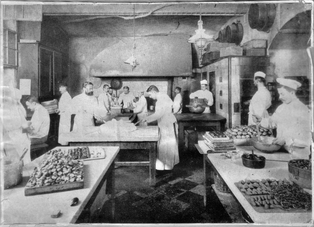 Bäcker arbeiten in  historischen Backstube Gerstner des 19. Jahrhunderts, umgeben von Teig und Gebäck.