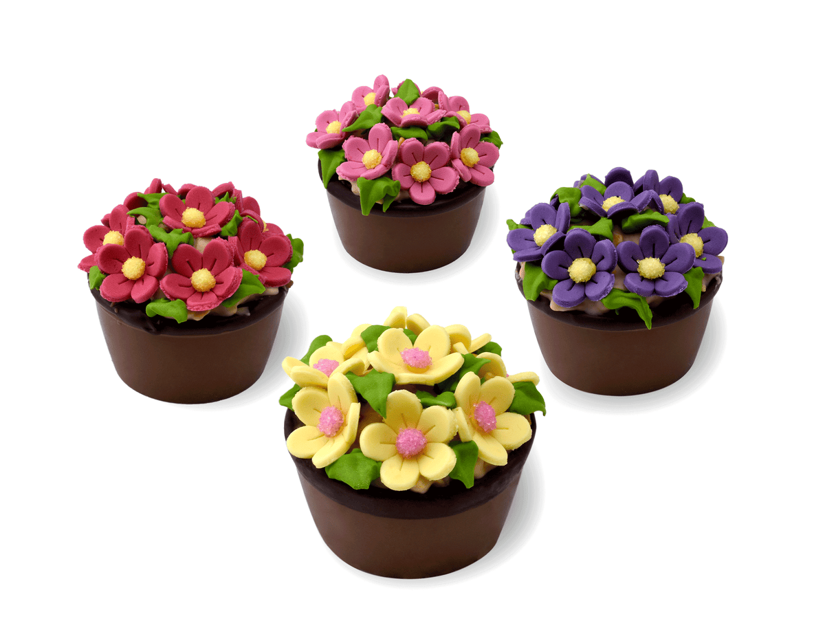 Vier Blumenkörbchen aus feinster Milchschokolade mit Zuckerblumen in verschiedenen Farben dekoriert. 